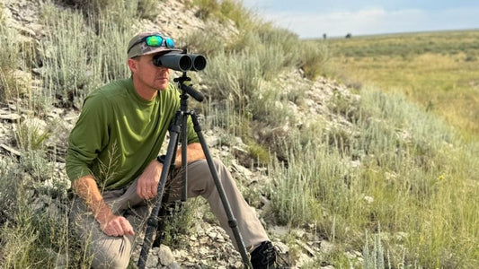 Big‑game hunter uses tripod binoculars to spot elk in sagebrush mountain hunting terrain