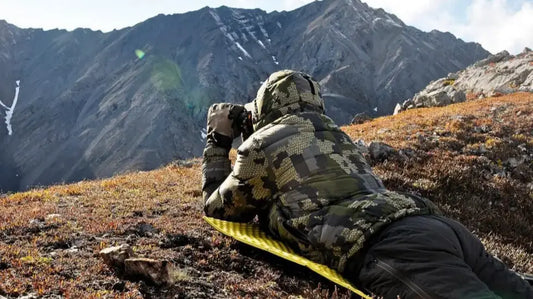 The rewilder scanned the mountainous terrain of remote Alaska with binoculars.