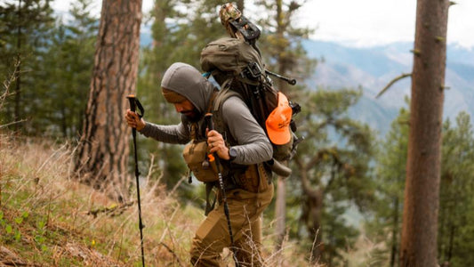 Elk hunter trekking through mountain forest with heavy-duty backcountry hunting pack