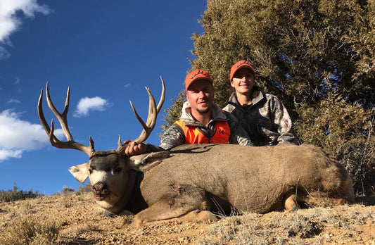 hunters with harvested mule deer buck on mountain hunting terrain