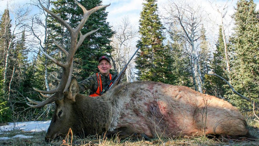 Backcountry hunter celebrates big bull elk harvest in mountain woodland