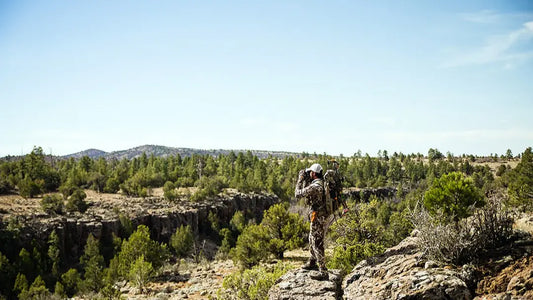 Hunter carrying best hunting backpack glassing elk across rocky backcountry canyon