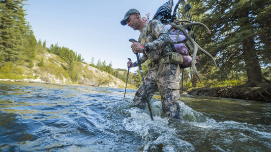 Elk Hunter Wading Mountain Stream With Heavy Game Hunting Backpack