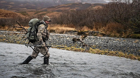 Hunter crossing water with a large frame hunting backpack on an elk hunt
