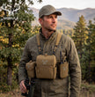 Moxule hunting gear field lifestyle shot, hunter wearing binocular chest harness with MOLLE radio pouch and accessories in fall backcountry woods