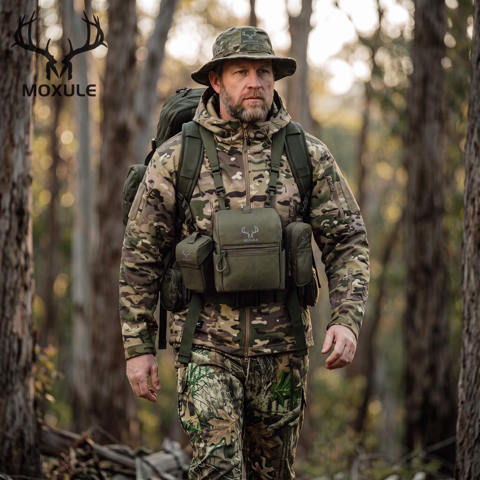 Hunter in camouflage walks through woodland wearing olive Moxule modular binocular harness, bino chest pack with detachable pouches for backcountry hunting